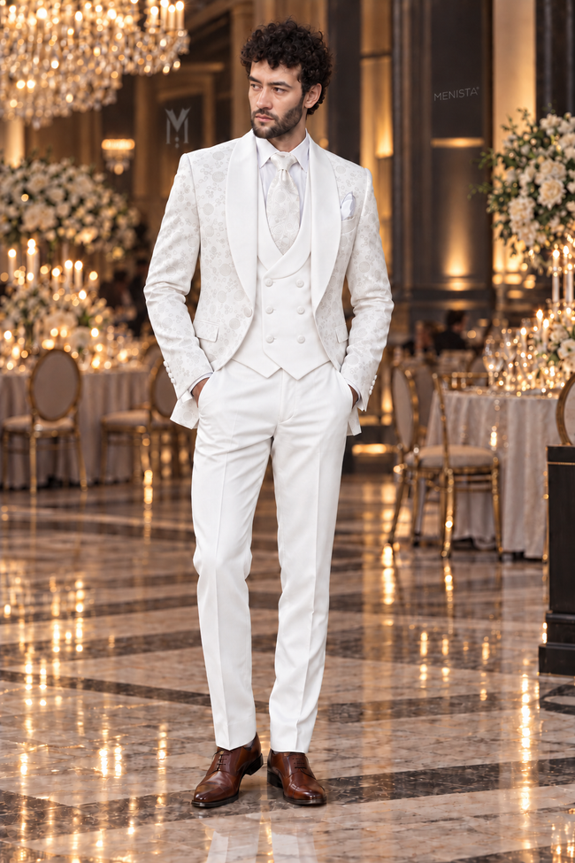 Montreux white jacquard three-piece tuxedo on Michael, front full-body view, with plain white waistcoat and trousers in an indoor wedding venue.