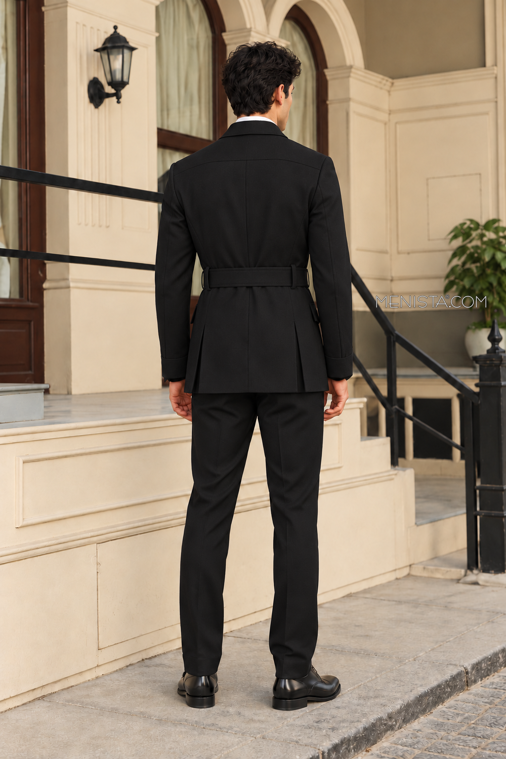 Back view of Auberon’s plain black belted hunter jacket with two rear side vents and straight-leg trousers.