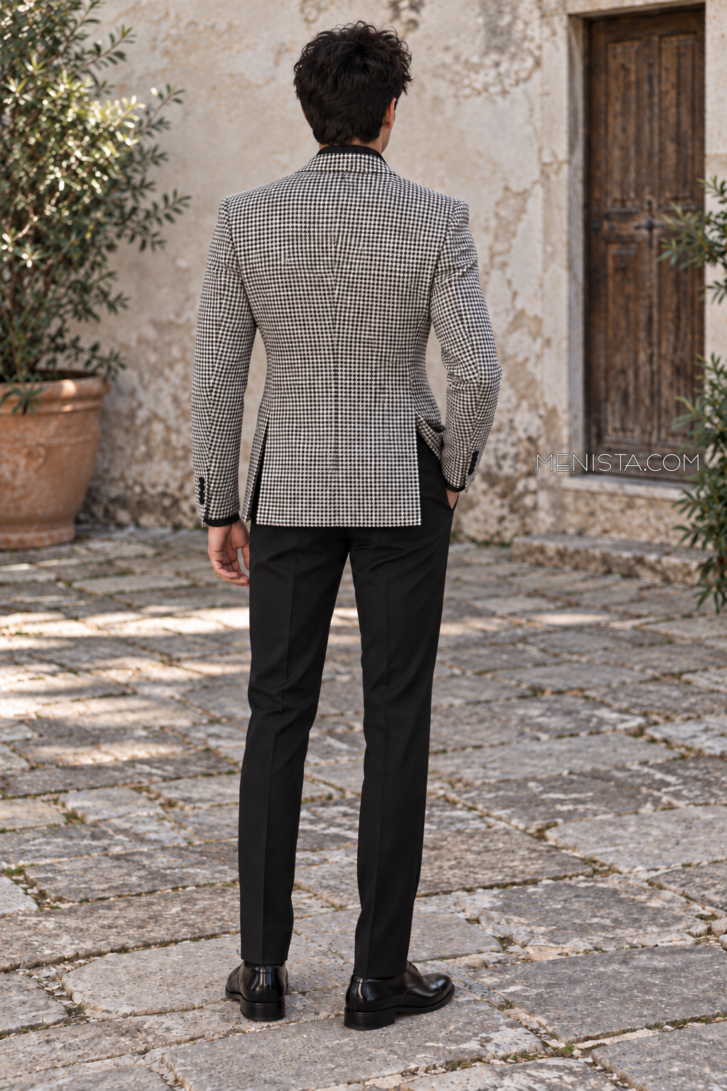 Evaristo houndstooth jacket back view showing two rear side vents and plain black straight-leg trousers.