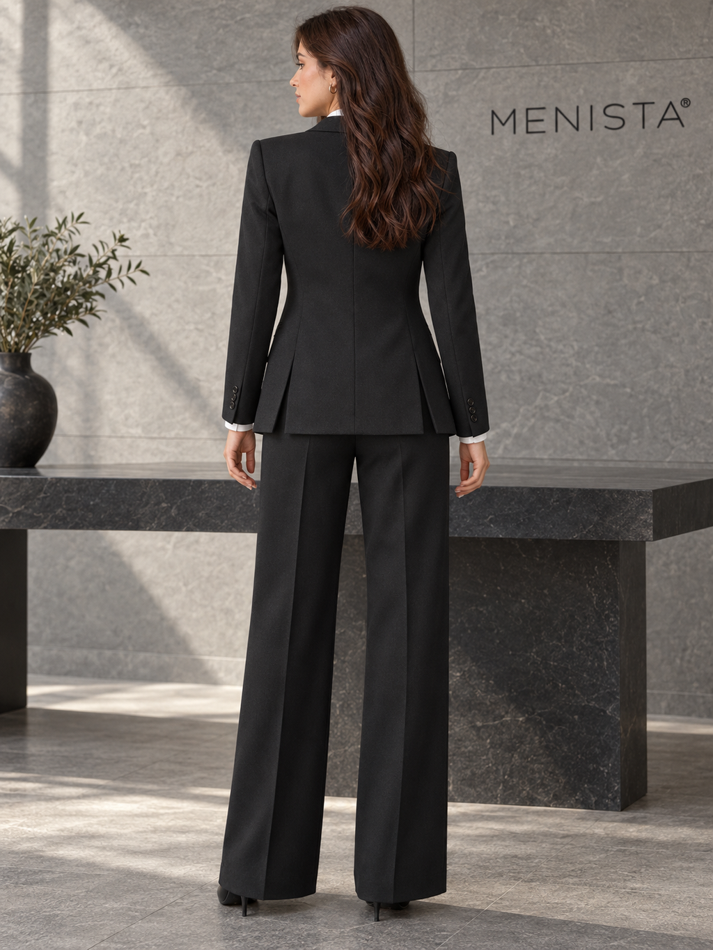 Rear view of women’s black two-button jacket and matching wide-leg trousers, showing the jacket’s twin side vents.