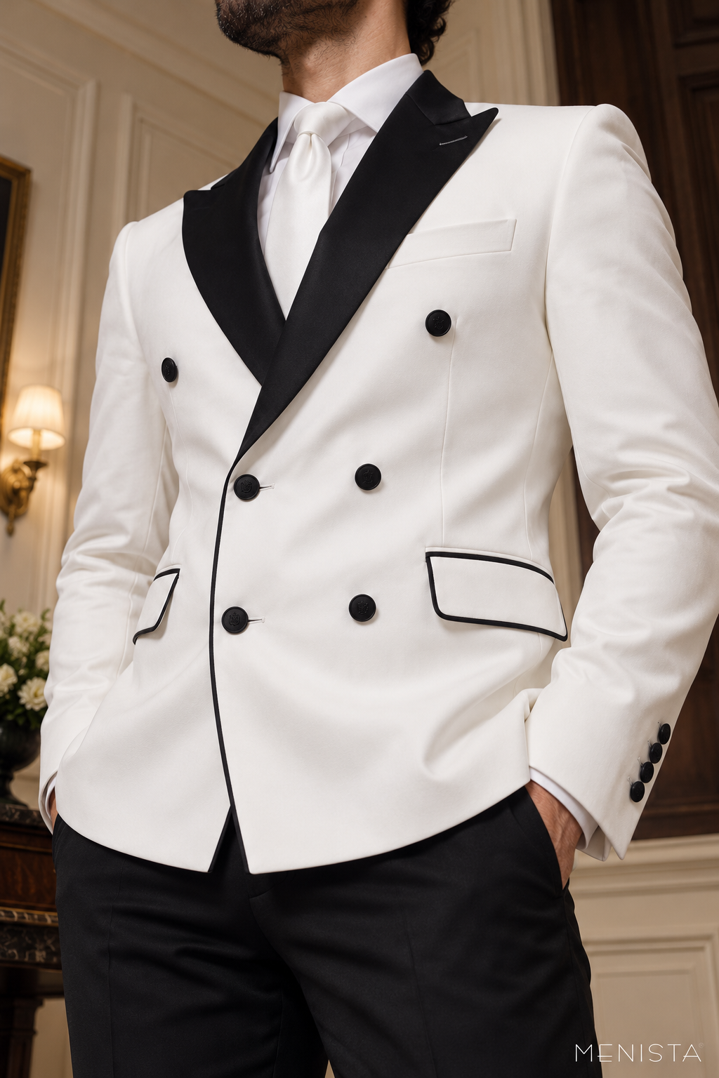 Close-up of Menista white tuxedo showing contrasting black peak lapels, six front buttons, pocket piping and fabric texture.
