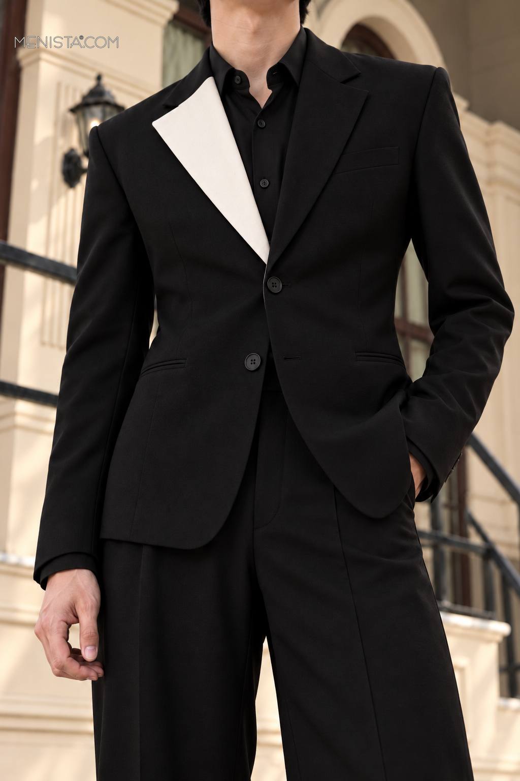 Close-up of Caldric’s ivory contrast lapel, black dress shirt and vertical two-button fastening.