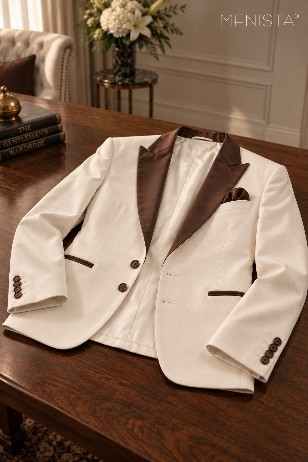 Menista ivory jacket laid flat with brown satin peak lapels, two front buttons, two buttonholes and four cuff buttons per sleeve.