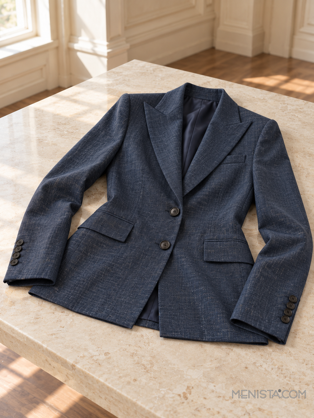 Opaline blue black heather linen jacket spread flat on a stone table with both sleeves supported.