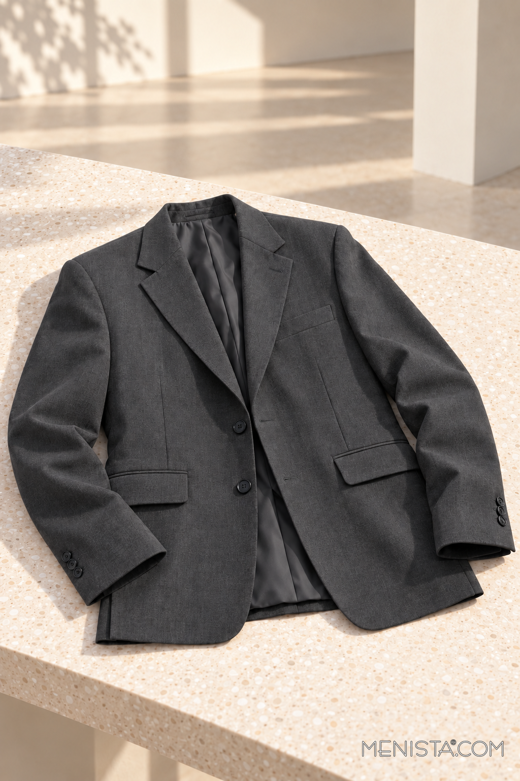 Bastian charcoal single-breasted jacket, jacket-only still life on a cream stone table.
